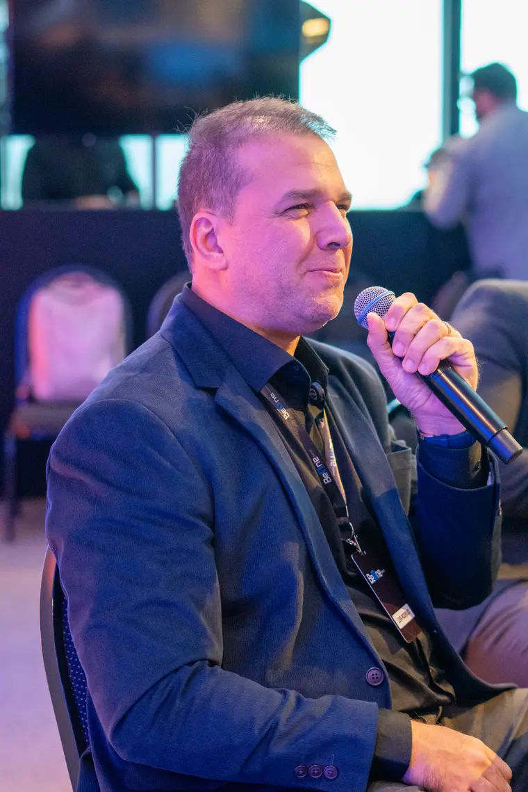 Rodrigo Andrade falando ao microfone em evento de negócios